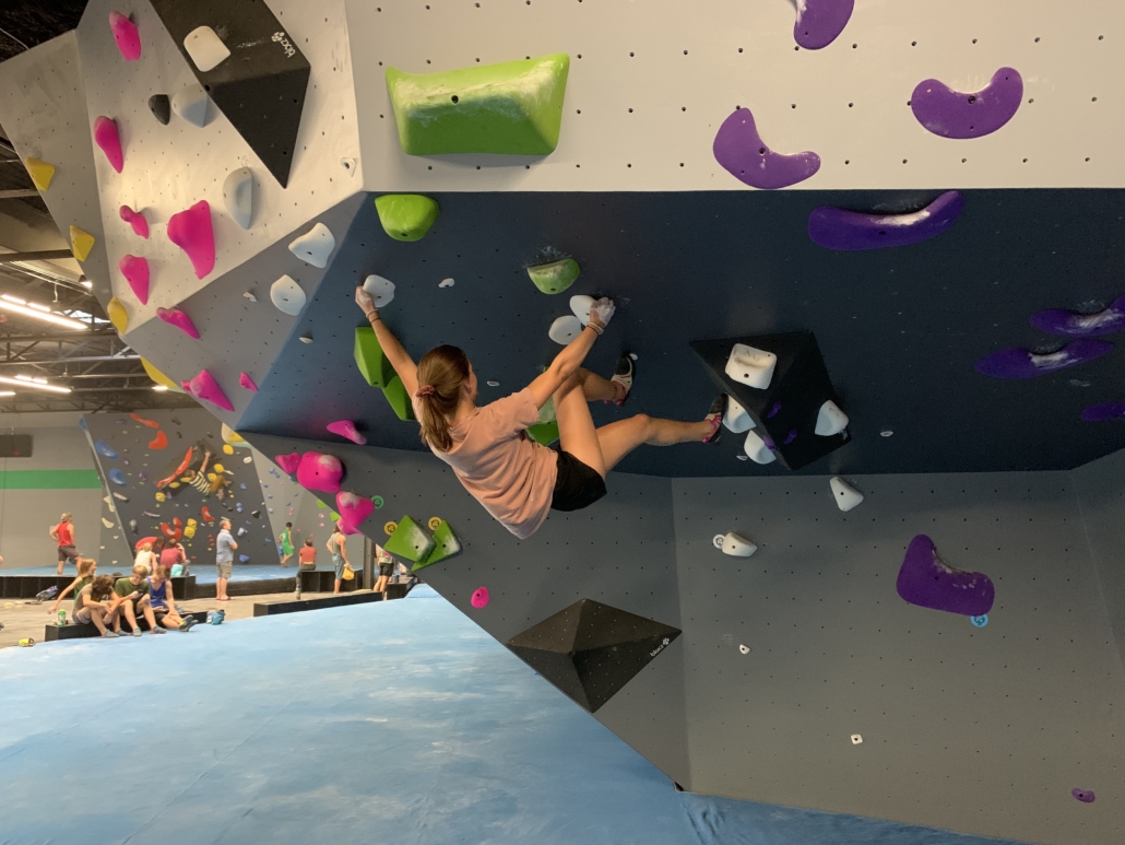 Girl hanging from overhang on climbing wall