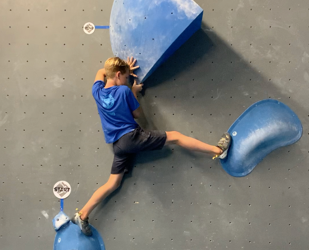 Bouldering competitor tries a competition boulder with marked start and zone holds during training camp.