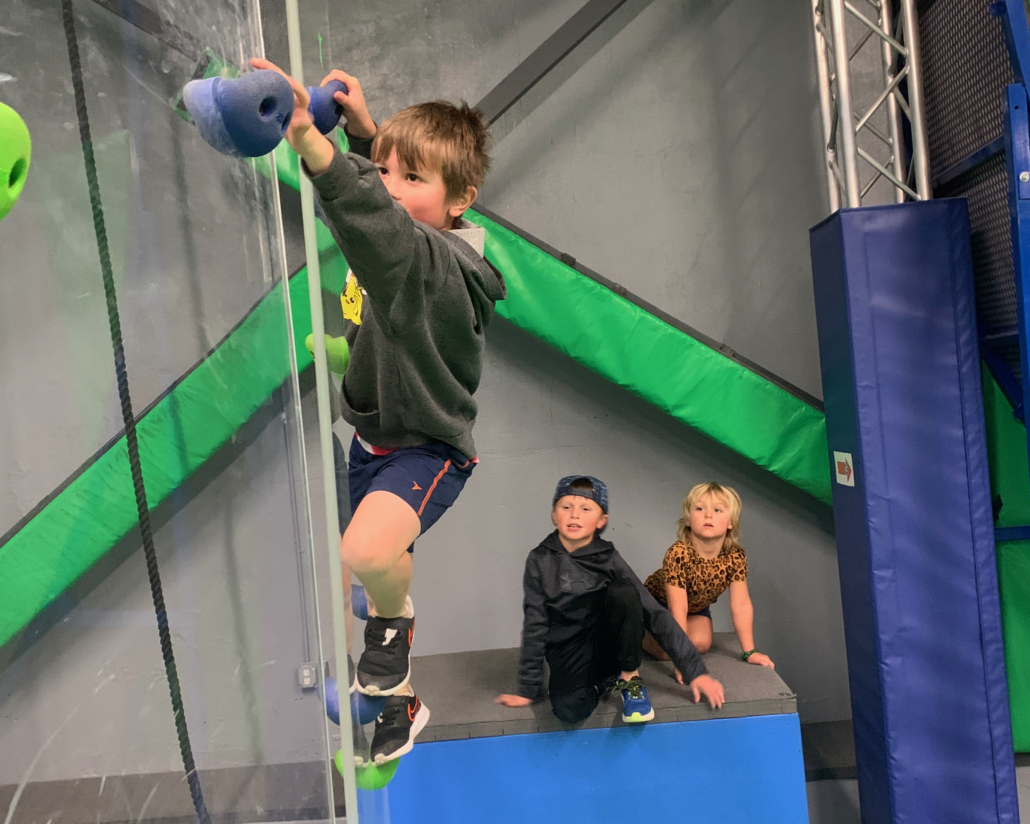 Child on swinging climbing wall of ninja course